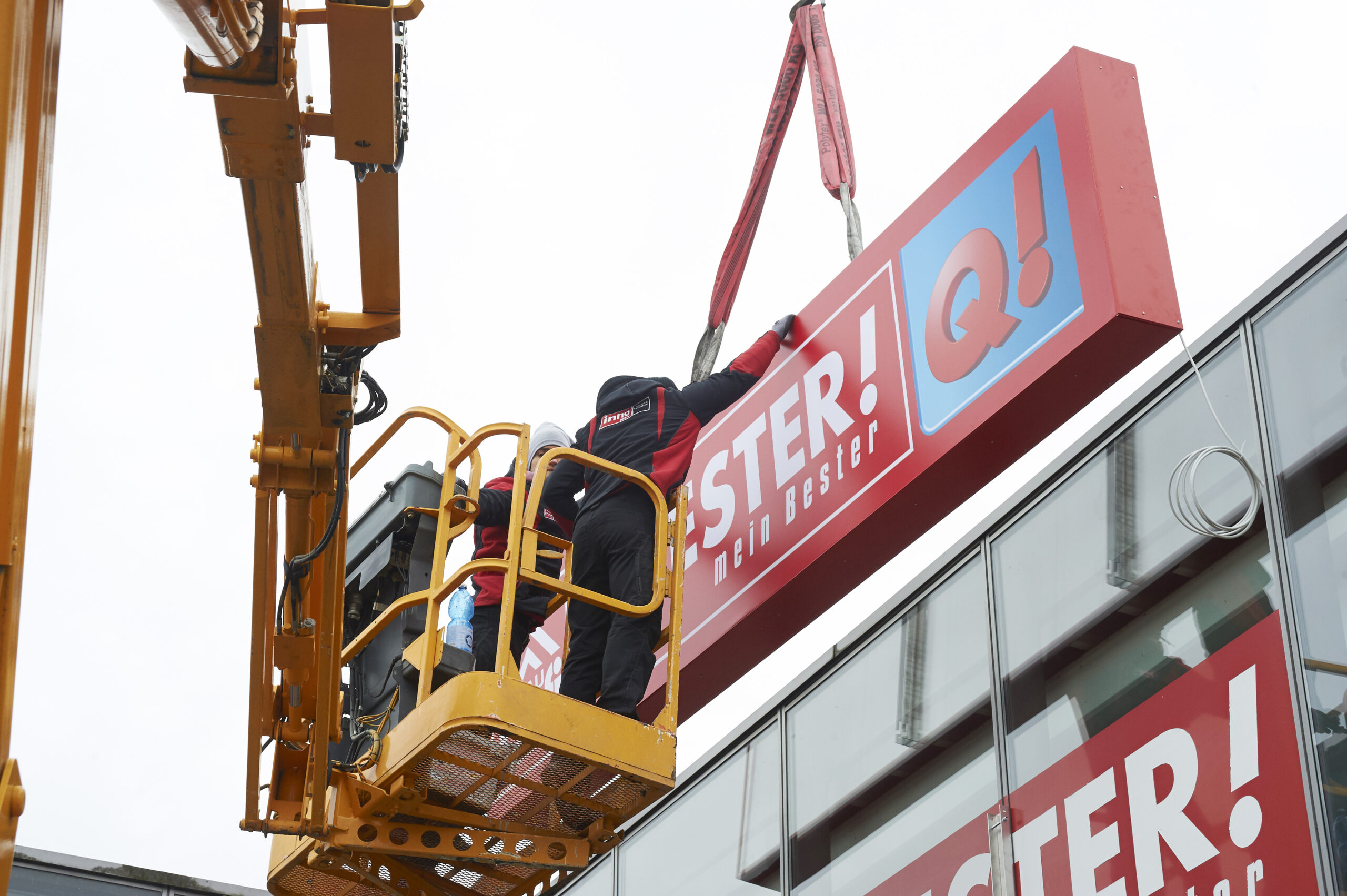 Handwerker montieren eine Werbeanlage an der Fassade