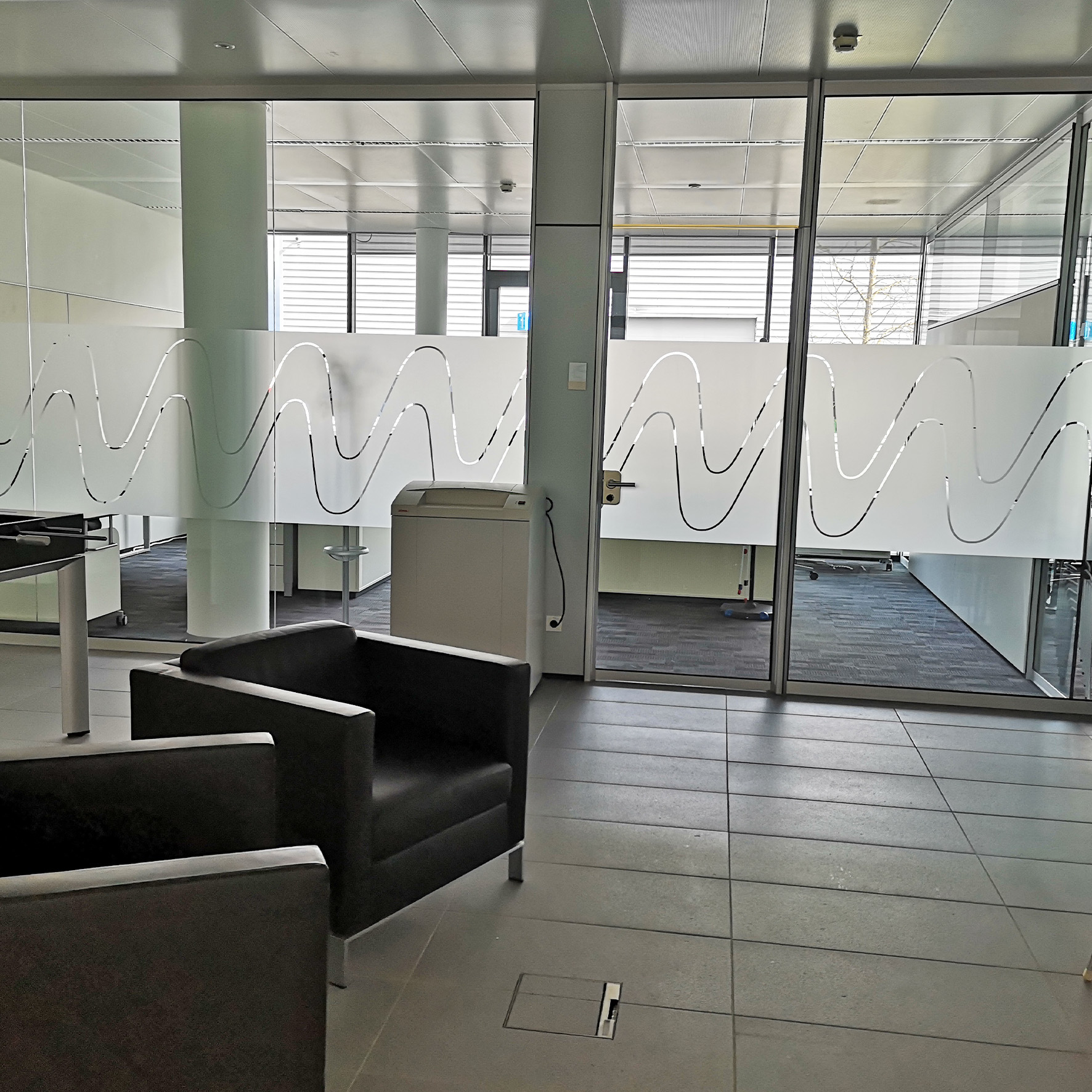 Glasfläche im Büro mit Anlaufschutzfolie mit Firmendesign kombiniert