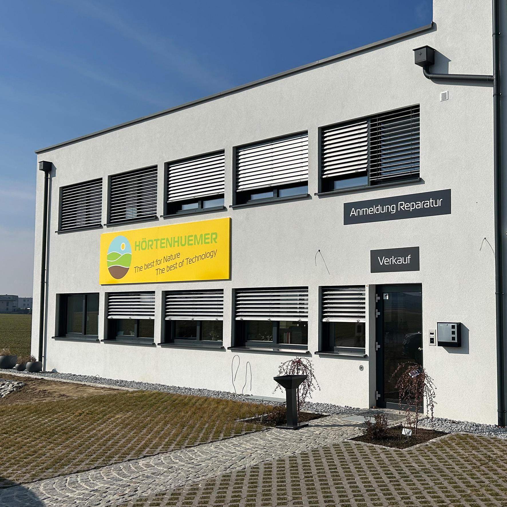 Fassadenschild mit Firmenlogo und Schriftzug an moderner Gebäudeaußenwand